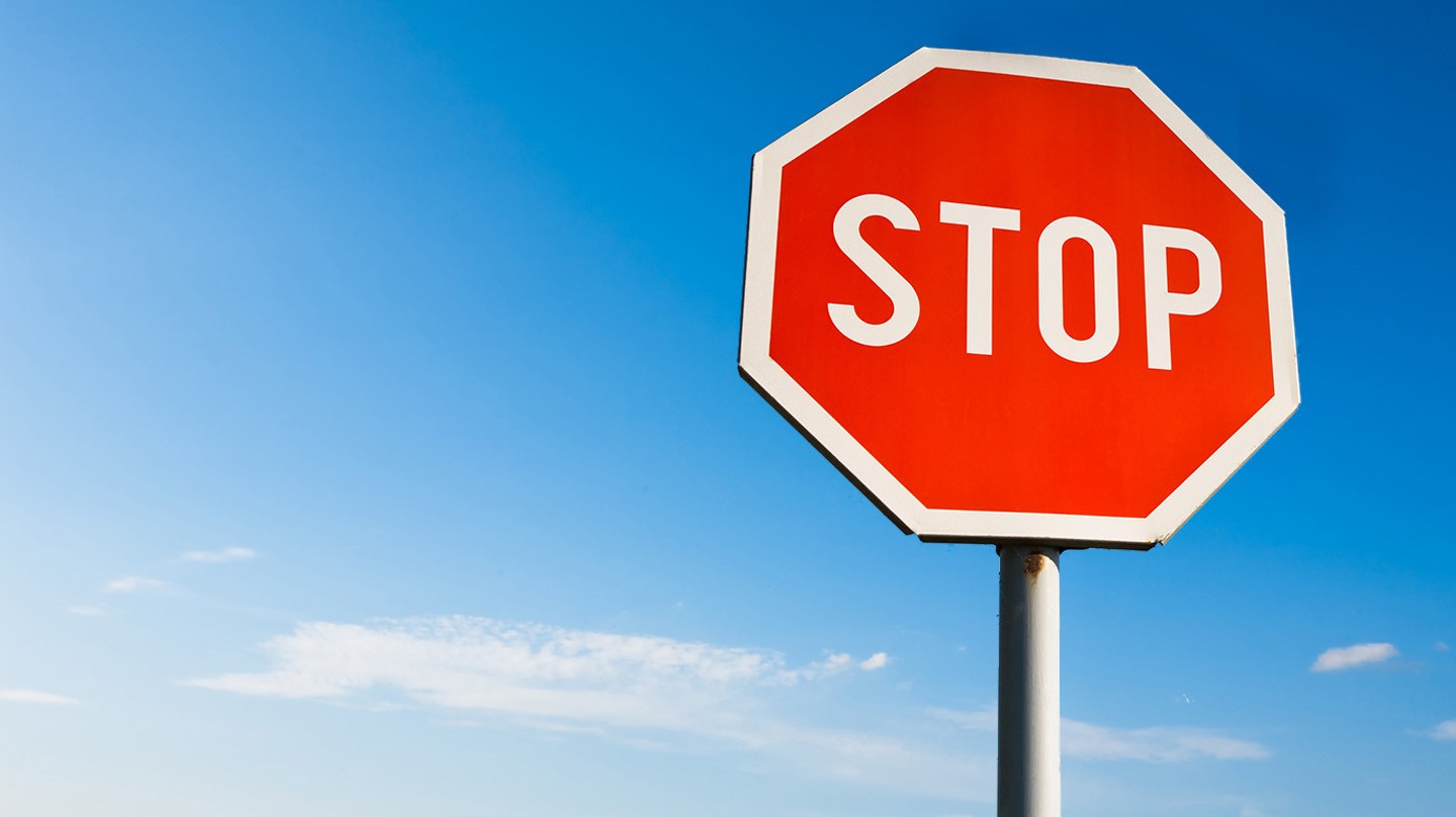 Verdacht auf Coronavirus? Stoppschild vor blauem Himmel.